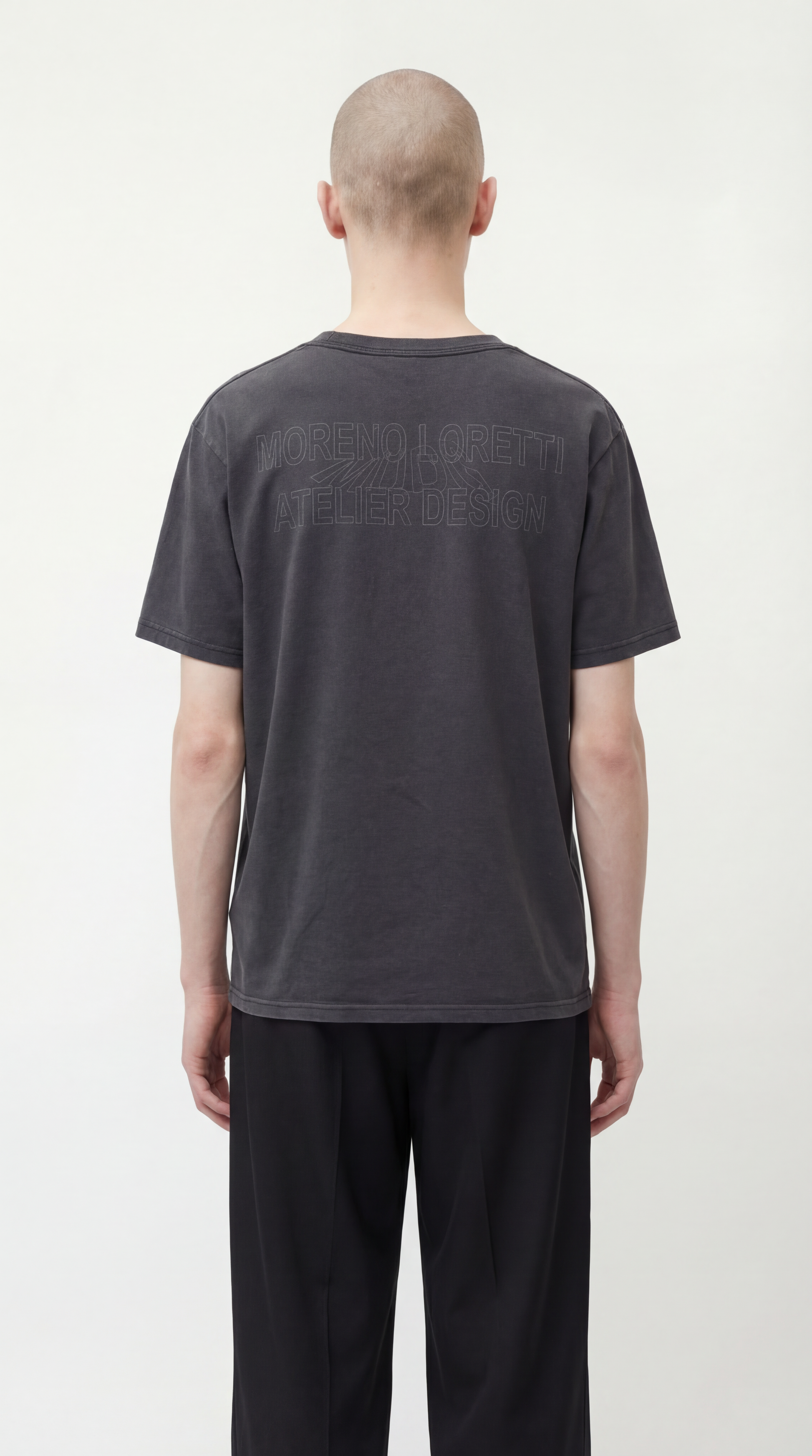 Person wearing a dark gray t-shirt with text on the back against a white background