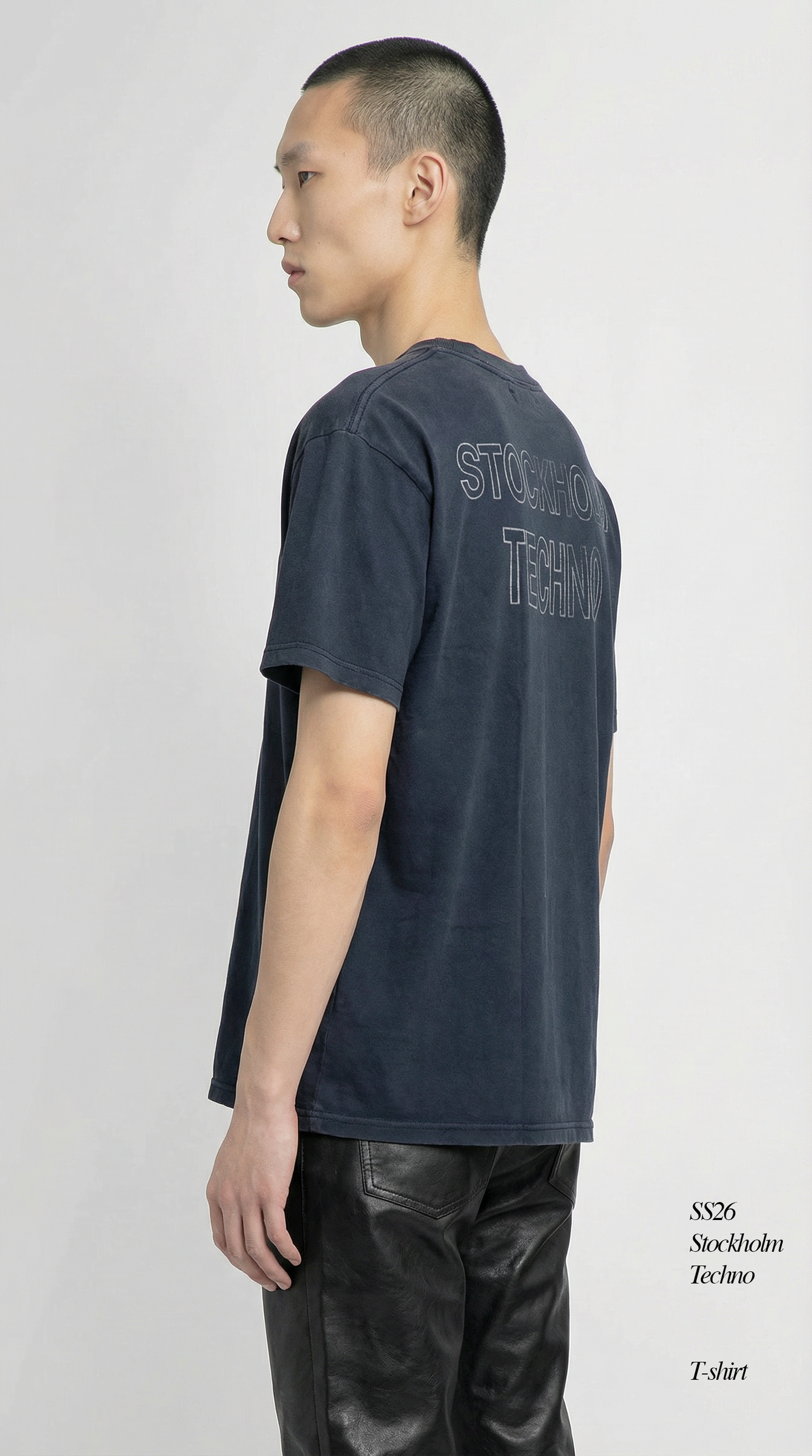 Man wearing a dark blue t-shirt with text on the back, standing against a white background